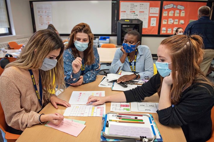 School of Education Interns work collaboratively around a desk.