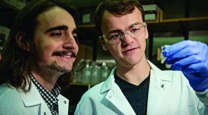 Scholarship medical students inspecting a small beaker.