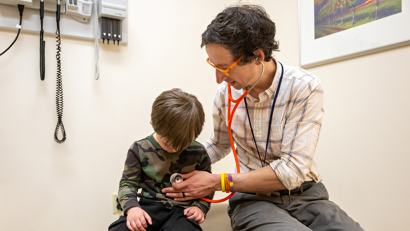 Dr. Koschmann listens to a child’s chest with a stethoscope in a medical clinic.