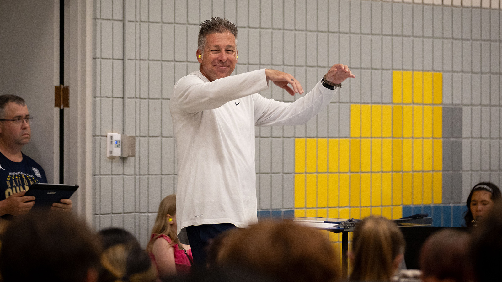 Michigan Marching Band Director John Pasquale conducting, smiling at the camera.