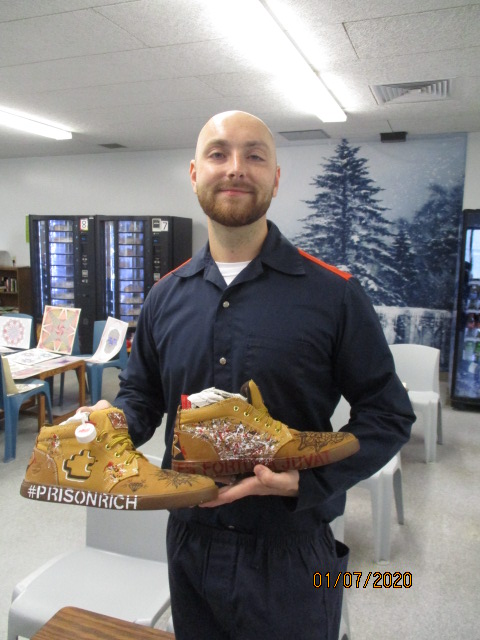PCAP artist Steven posing with a pair of shoes that he painted.