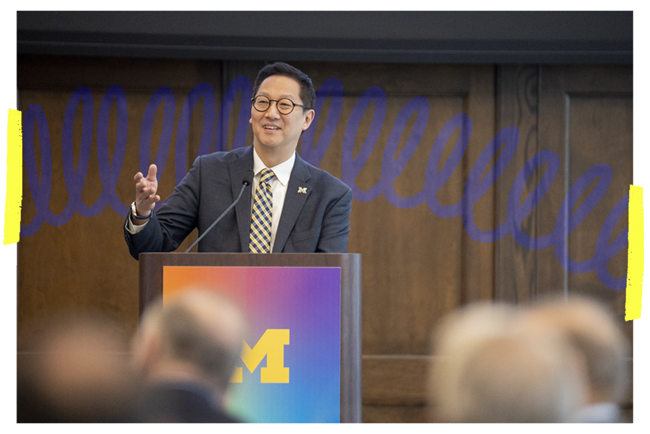 President Ono standing at a podium with the Block M on the front.