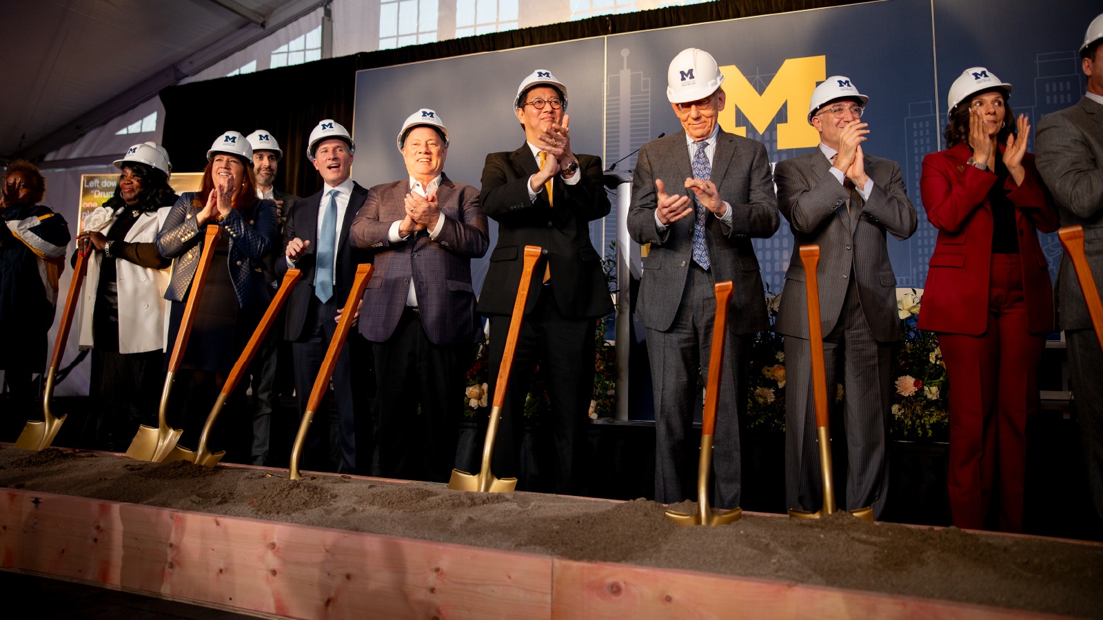 Men and women in hard hats with a Block M holding shovels at the groundbreaking of the University of Michigan Center for Innovation