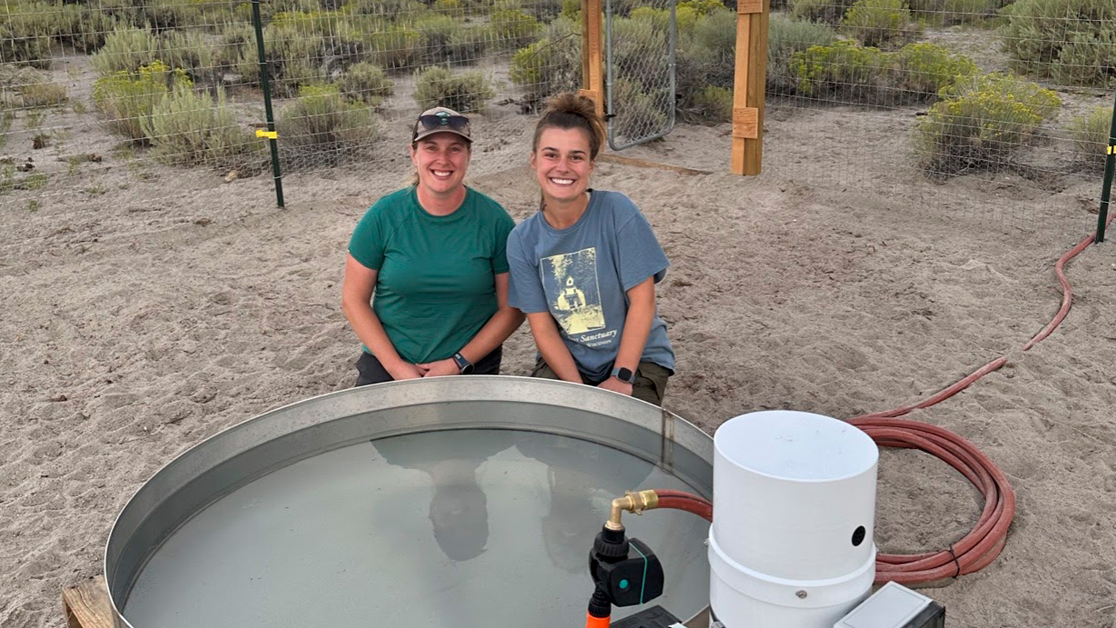 Two SEAS researchers smiling next to an evaporation pan they installed.