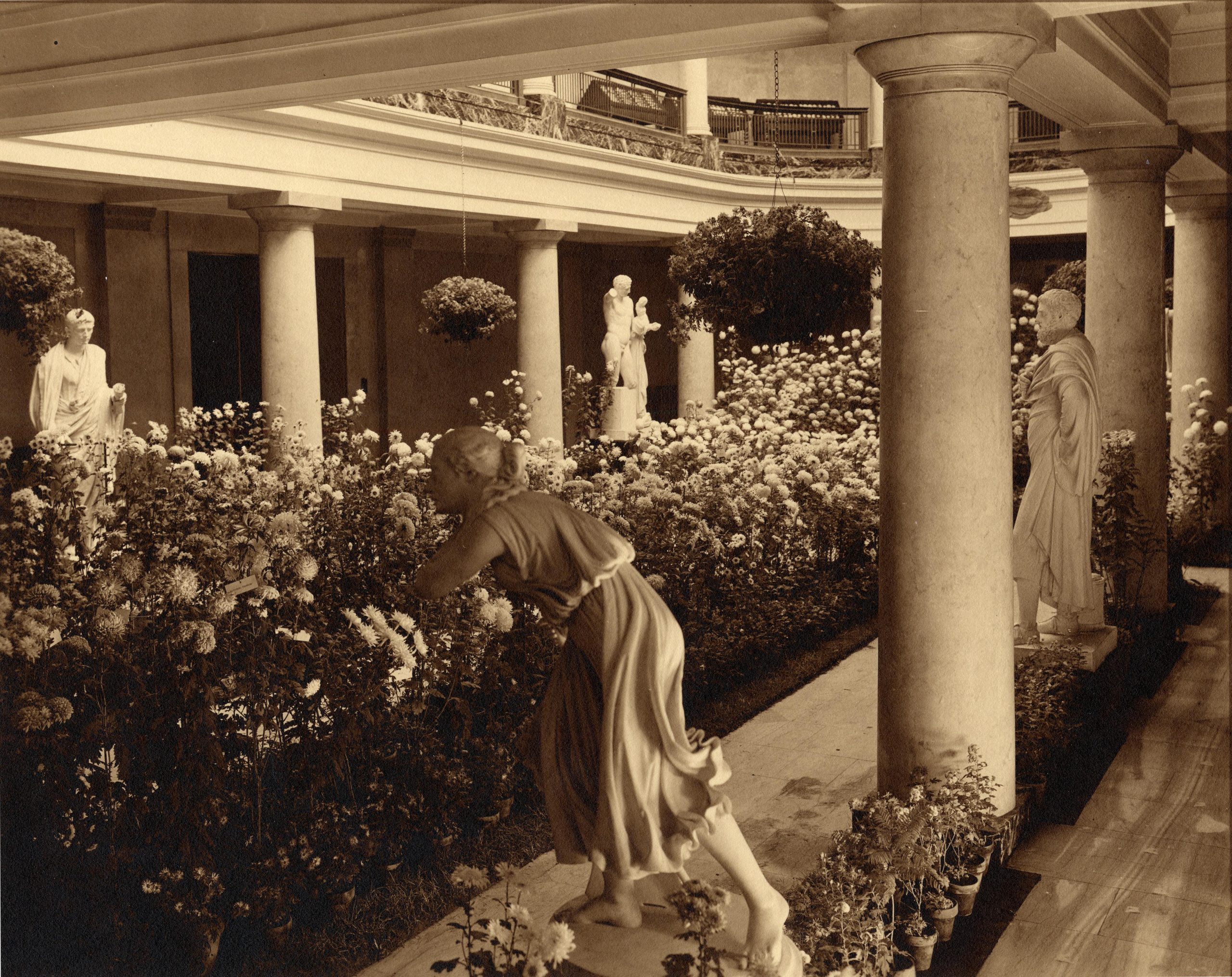 A statue of a woman leaning over the flowers in the garden.