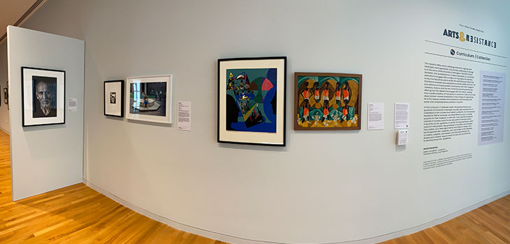 A wall in a gallery with artwork hung on it.