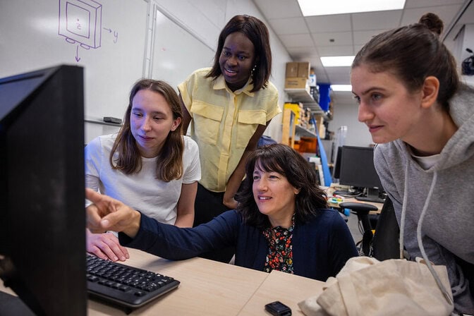 Kathleen Sienko and three graduate students look at a computer monitor, analyzing body movement data.