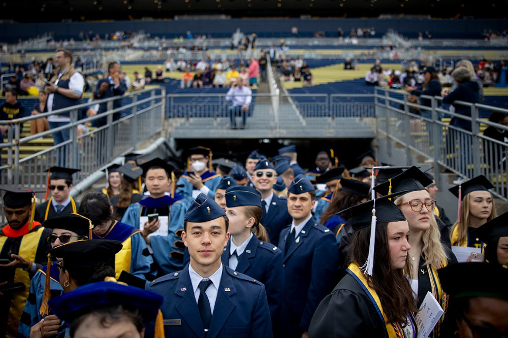 A crowd of ROTC students in uniform entering the Big House. One student in the center is looking into the camera.