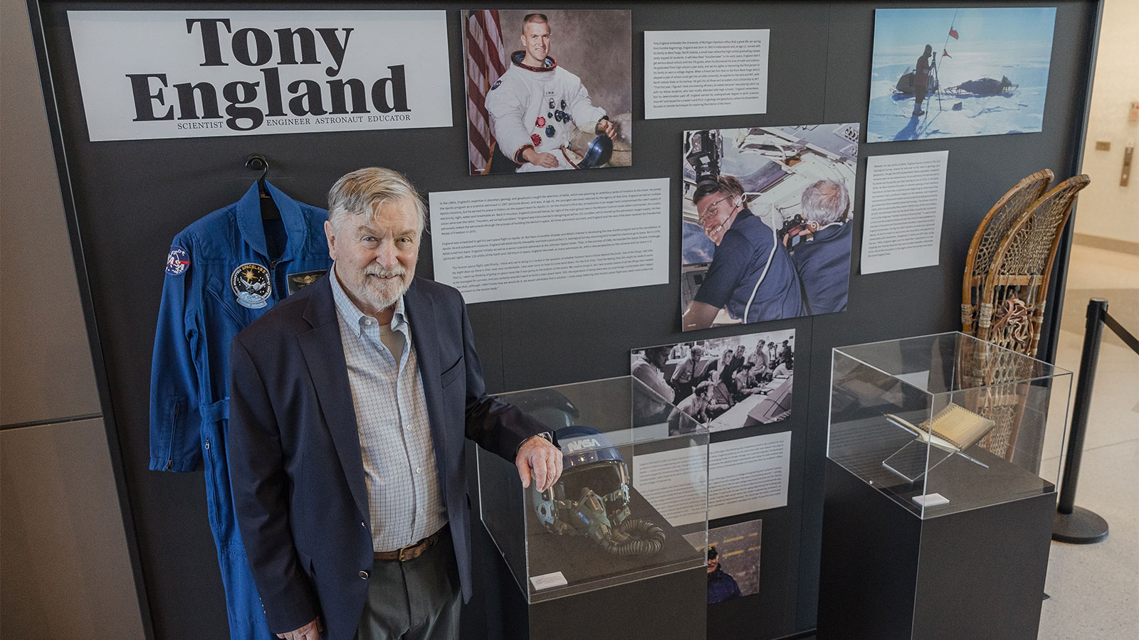 England in front of a display of memorablia from his work at NASA and the U.S. Geological Survey including his uniform and helmet from the 1985 Space Shuttle Challenger mission and snow shoes from his USGS mission in Antarctica. Photo by InnerCircle Photography.