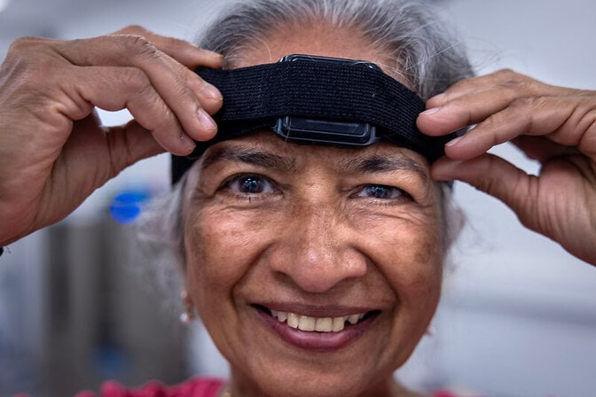 Close up of Geeta Peethambaran's face as she positions a sensor on her forehead to participate in a balance training study.
