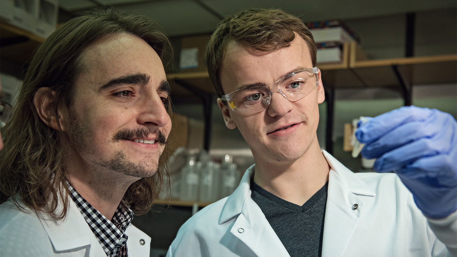 Two men in lab coats examining research equipment.