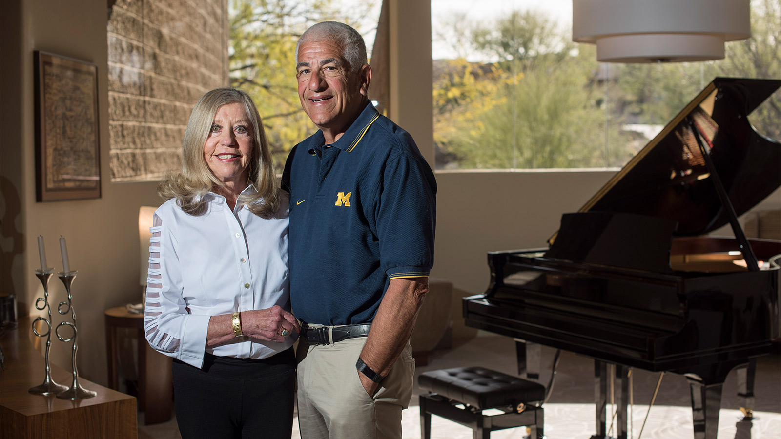 Richard and Susan Rogel standing next to each other and smiling, with a piano in the background.