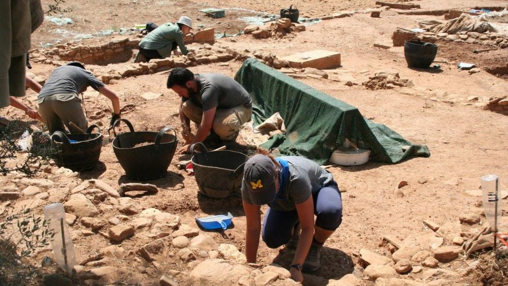 Researchers, including one wearing a U-M hat, at a dig site