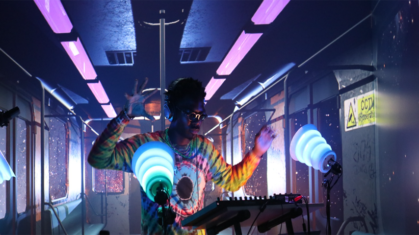 A drummer wearing headphones performing in a virtual space with purple and blue lighting 
