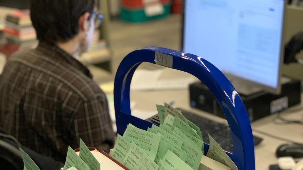  student inputting information into computer on library materials into on-line catalog 