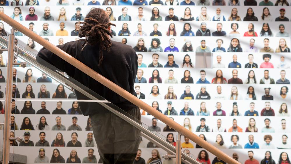  Student looking at wall with photos of other students 