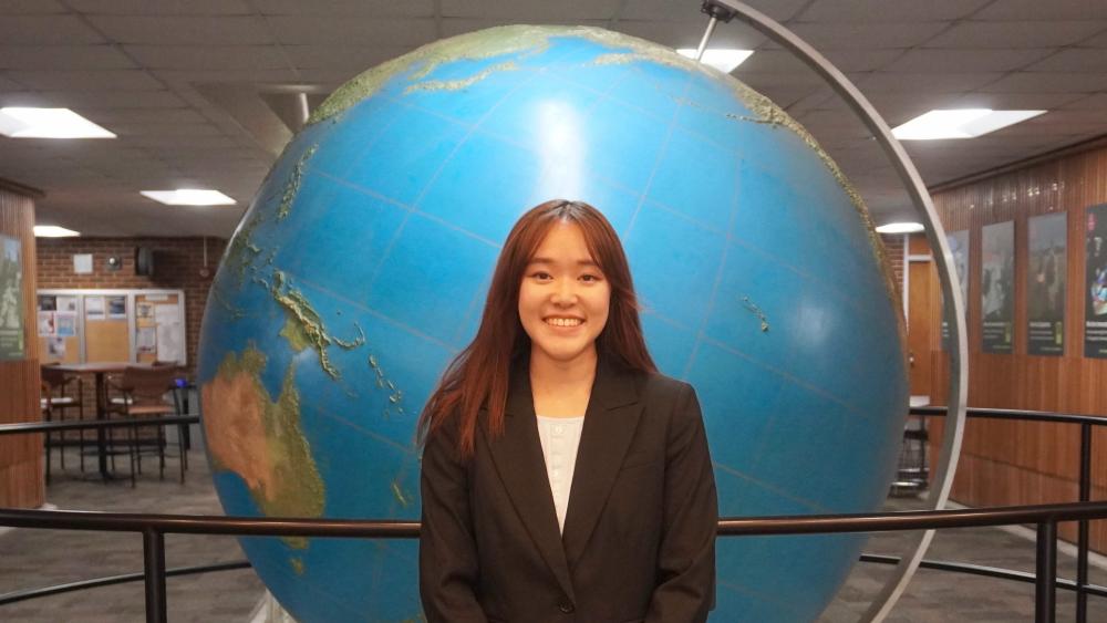  PitE student standing in front of a globe 