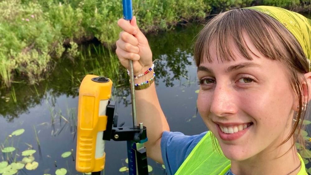 Student smiling while doing fieldwork