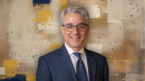 Arthur Lupia in suit and tie in front of an abstract background.