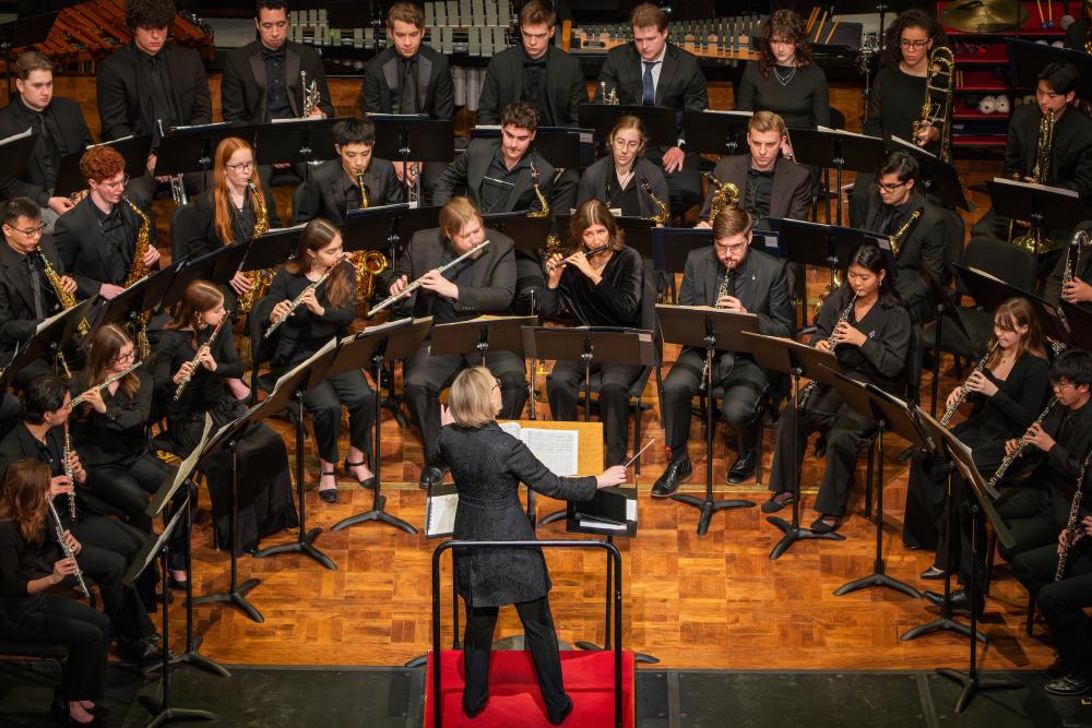  Students in the winds section of the University of Michigan symphony orchestra band look to the conductor with instruments in hand during a staged performance. 