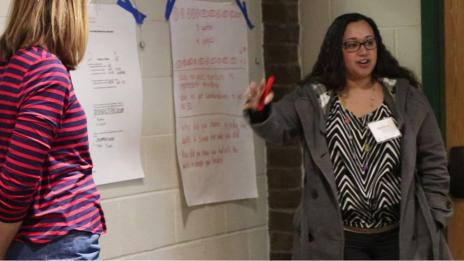 Two women teaching in front of a classroom.