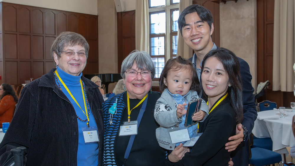 A group of five people including a baby smiling at the camera