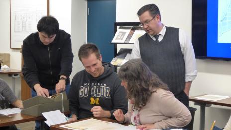 Curator and students looking at historical materials