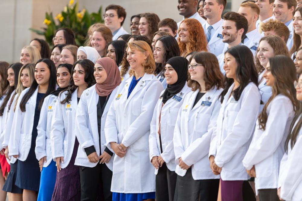 Photo of Dean and students gathered on steps at white coat ceremony