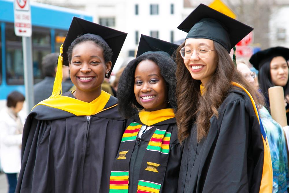Three black graduates wearing caps and gowns