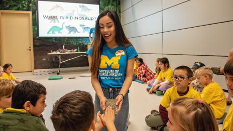 Museum student docent showing school children a fossil