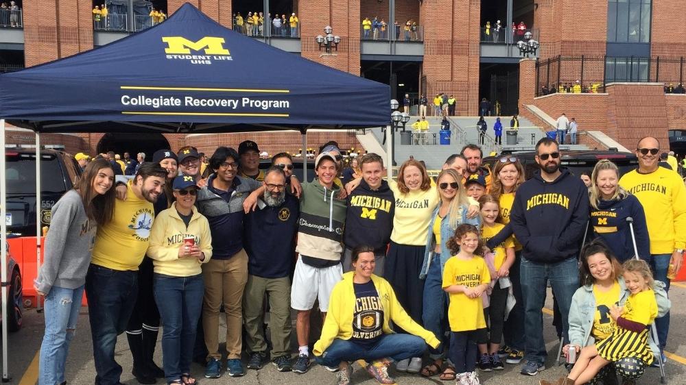 A group of students and staff at a Michigan football tailgate