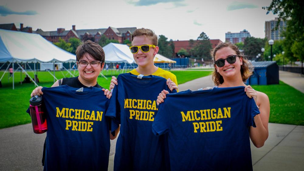 Three students holding t-shirts that say Michigan Pride