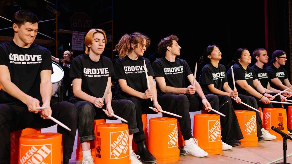 Students playing buckets on a stage