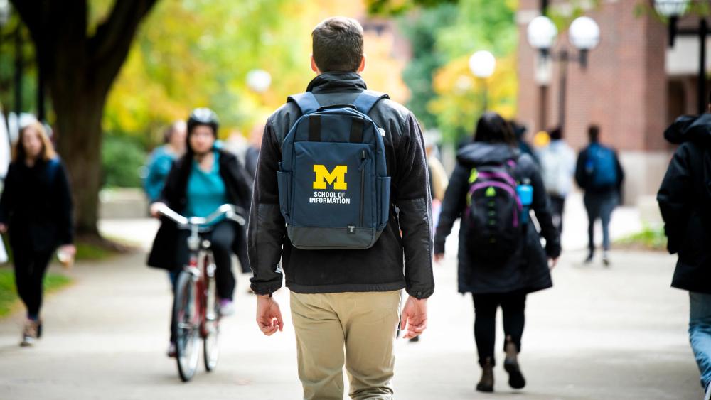 Student wearing UMSI backback on diag.