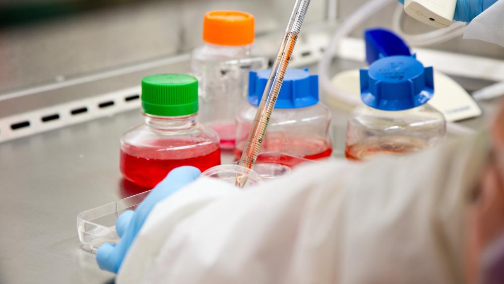 Up close of gloved hands transferring liquid into a test bottle