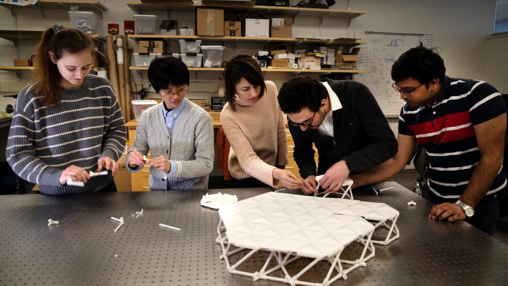 PhD student gather around work table to connect 3D printed parts