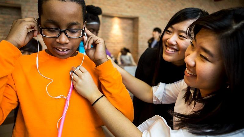 Two students listening to the heartbeat on a child