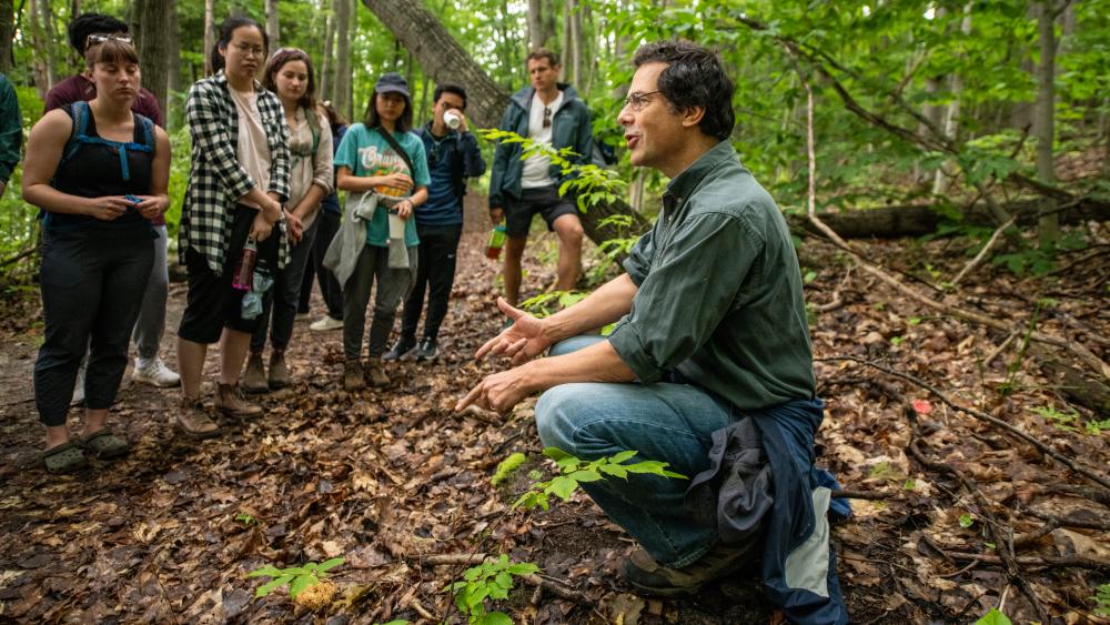 Instructor kneeling in woods in front of class