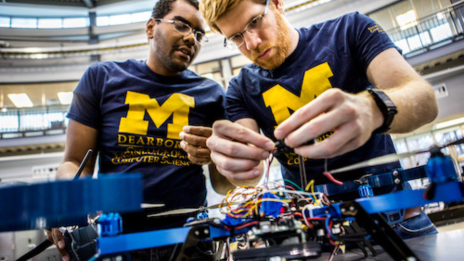 Two students wiring a machine