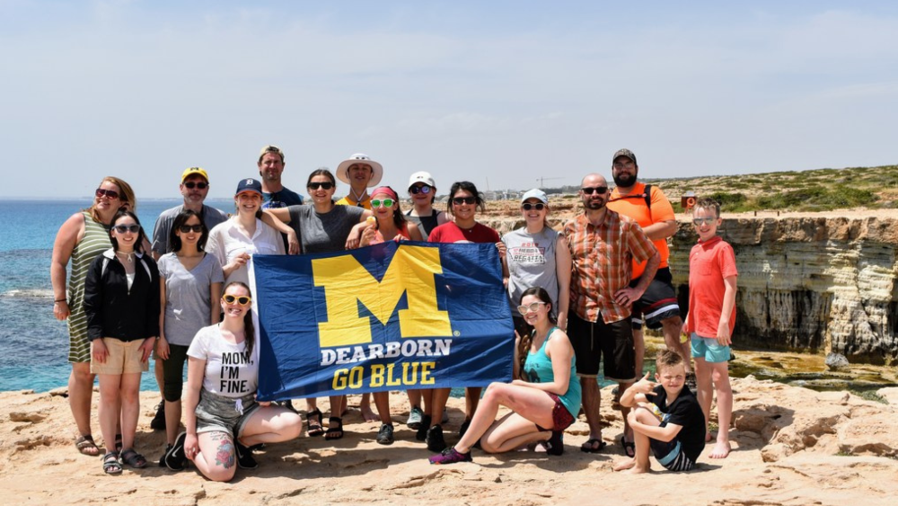 UM-Dearborn studying abroad, holding UM-Dearborn flag