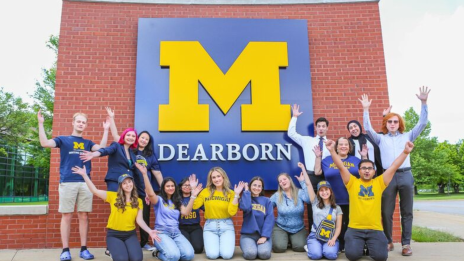 Students posing in front of UM-Dearborn brick logo outside