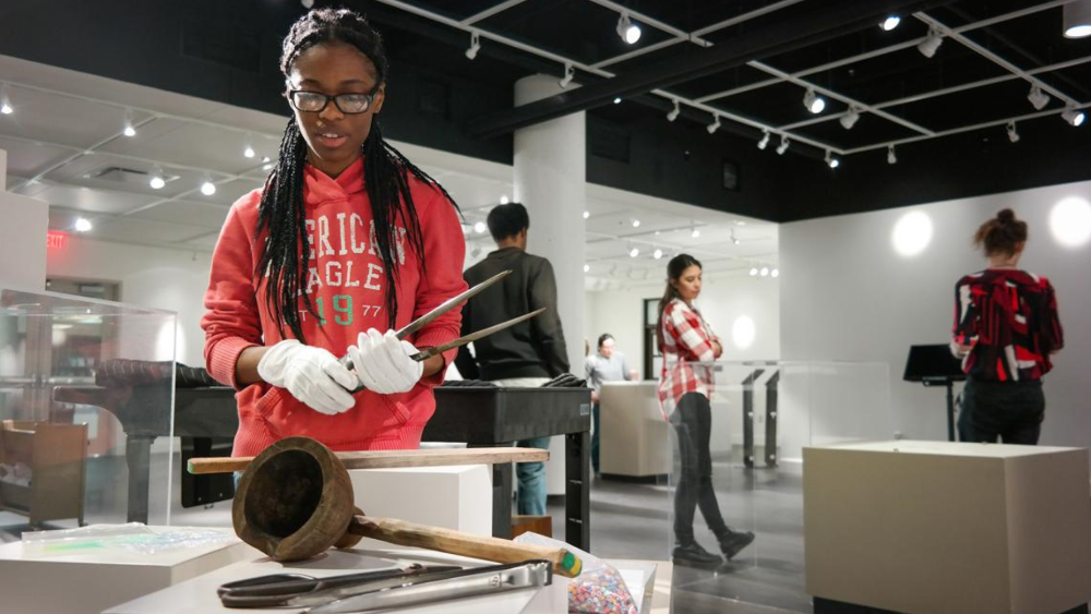 Biology student carefully handles the ancient artifacts that are apart of a student-curated exhibition opening