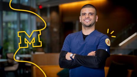 Josh Truchan posing with a smile and his arms crossed at the School of Nursing.