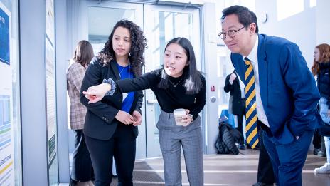 President Ono looking at a poster presentation with two students