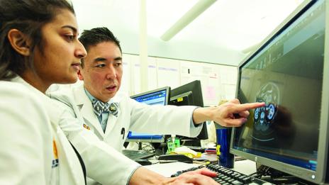 Male researcher points to computer screen with female researcher looking at the computer