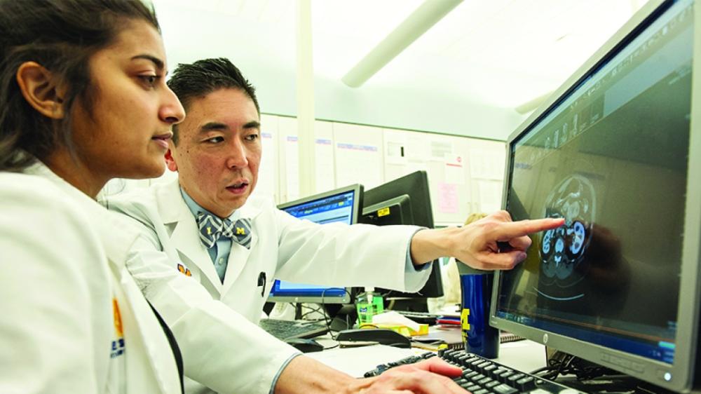 Male researcher points to computer screen with female researcher looking at the computer