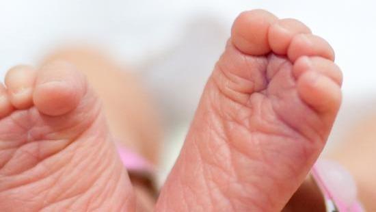 Up close of the bottoms of two infant feet with toes curled