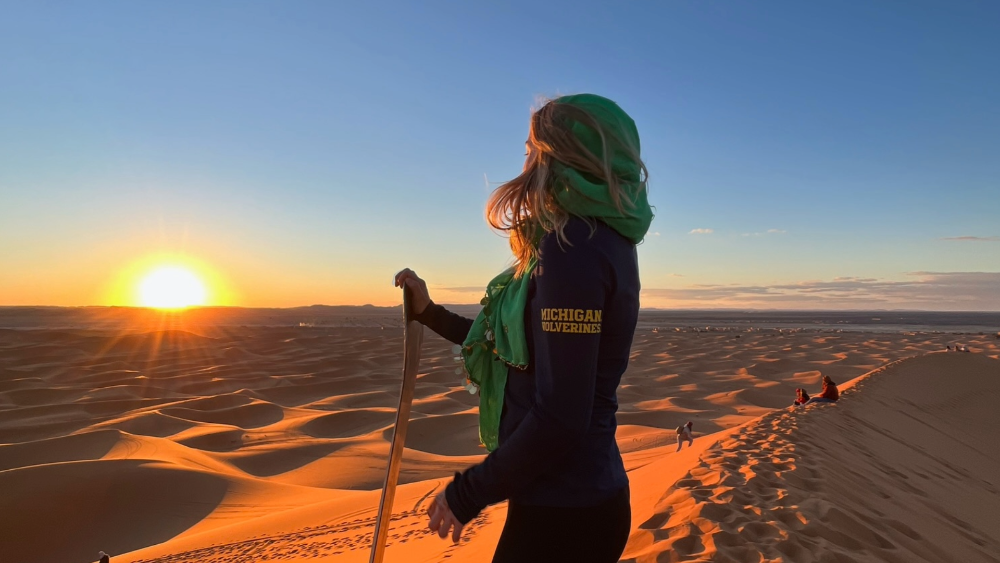 Student overlooks a sand desert and sunset