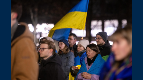 A group stands outside in the winter holding Ukrainian flags