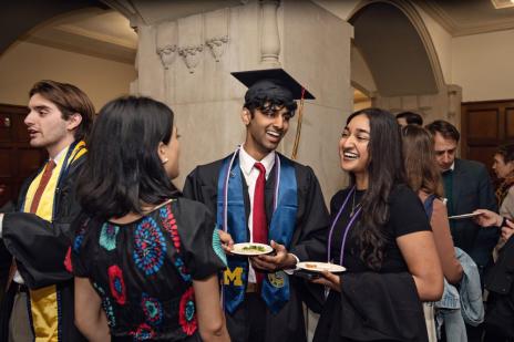 Students laughing together while socializing in cap and gown